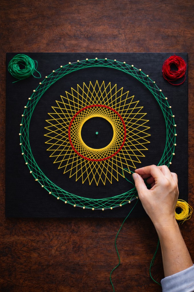 Tejido a mano de un mandala de hilo sobre tabla, con hilos de color